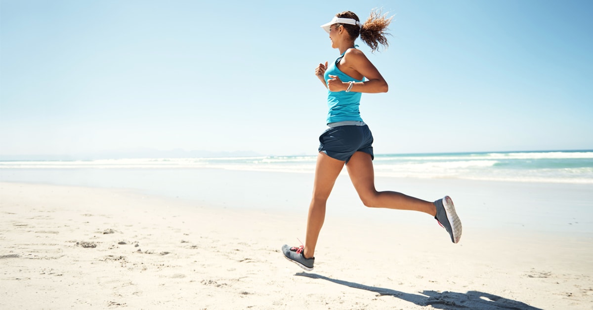 Ragazza con scarpe per correre sulla sabbia al mare