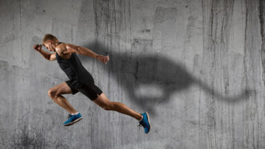 Strong athletic man sprinter, running on dark wall background wearing in sportswear. Sport and fitness motivation