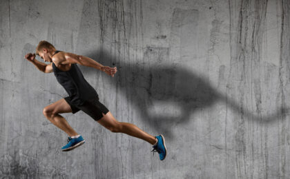 Strong athletic man sprinter, running on dark wall background wearing in sportswear. Sport and fitness motivation